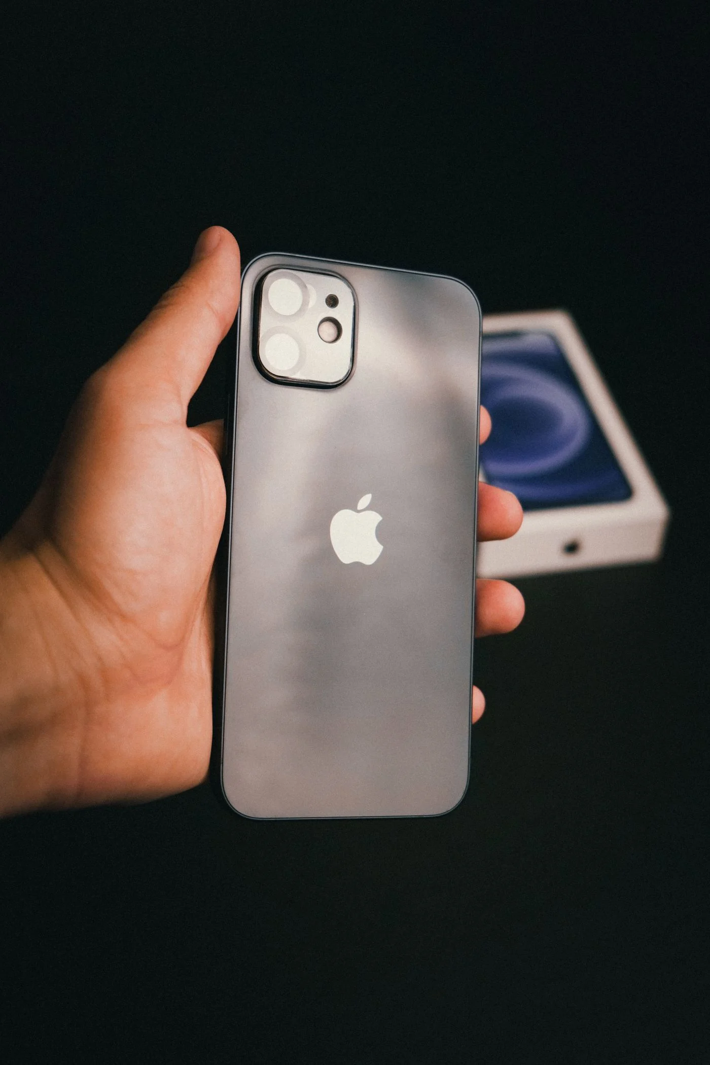 Hand hält ein neues iPhone vor der Originalverpackung