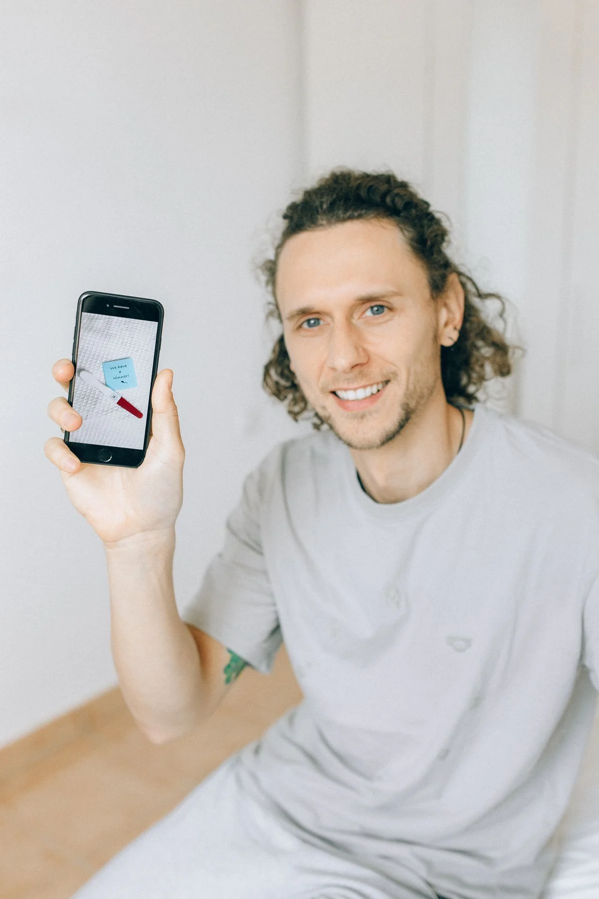 Lächelnder Mann hält sein Smartphone in die Kamera