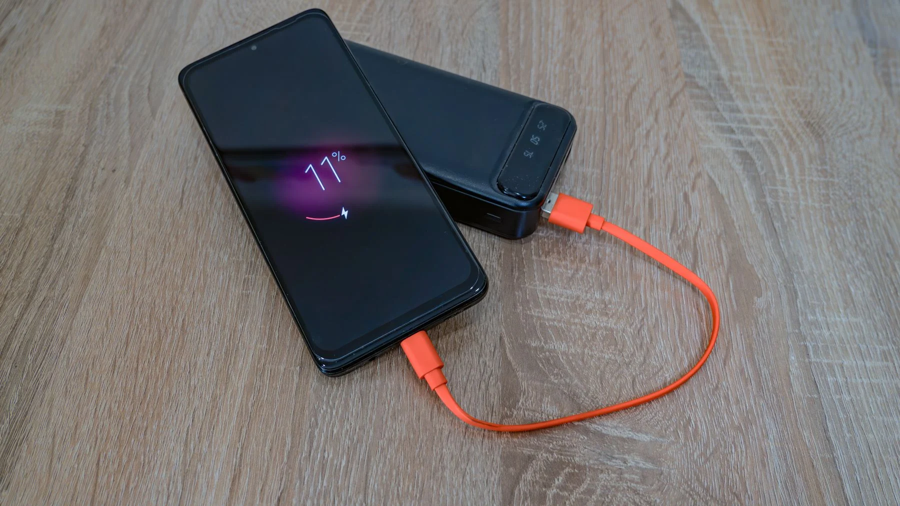 Smartphone mit orangem Ladekabel
