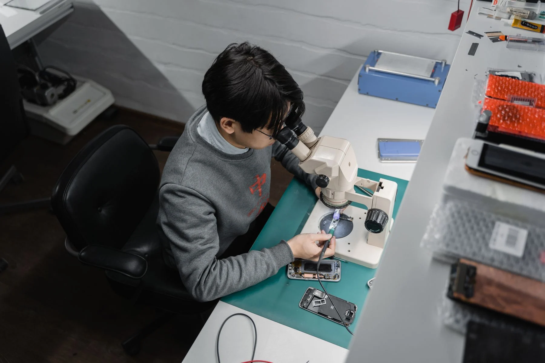 Techniker repariert ein Smartphone unter dem Mikroskop an der Werkbank